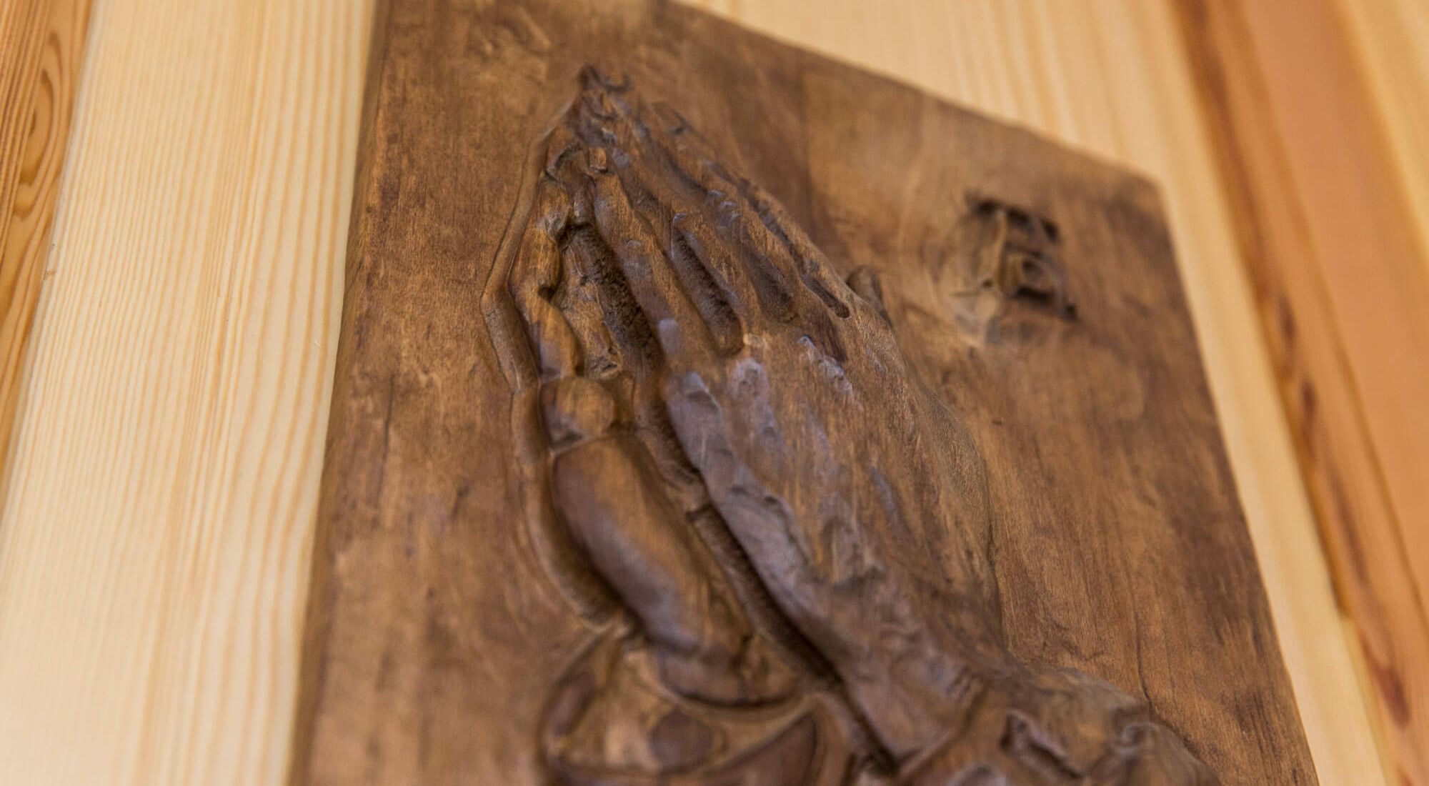 Holzbild mit betenden Händen an einer Holztür