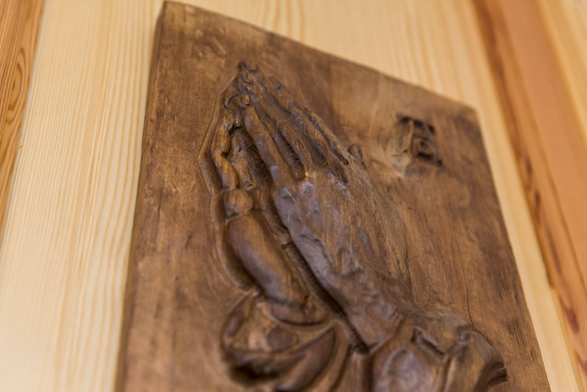 Holzbild mit betenden Händen an einer Holztür
